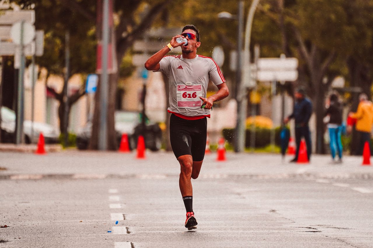 Coureur qui boit à la bouteille en pleine course sur route